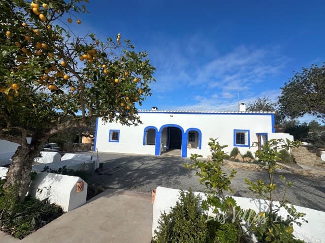 Traditional whitewashed facade with a blue door and an orange tree at Villa Girasol, Santa Gertrudis, Ibiza