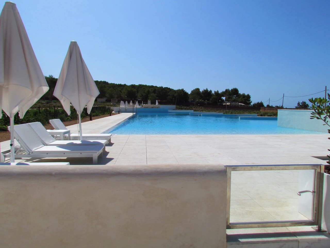 Sun loungers and parasols along the pool behind a glass balustrade, Ibiza