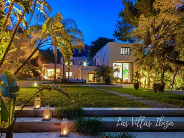 Front line house lit at dusk among mature palms, Sant Jordi de Ses Salines, Ibiza
