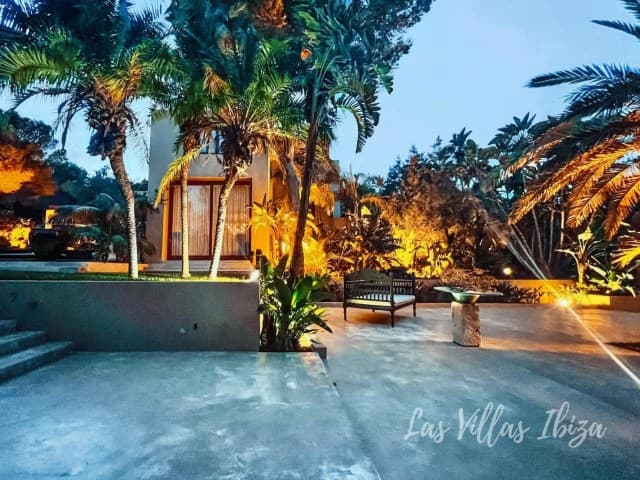 Swimming pool and mature palms lit at dusk at a front line house, Sant Jordi de Ses Salines, Ibiza
