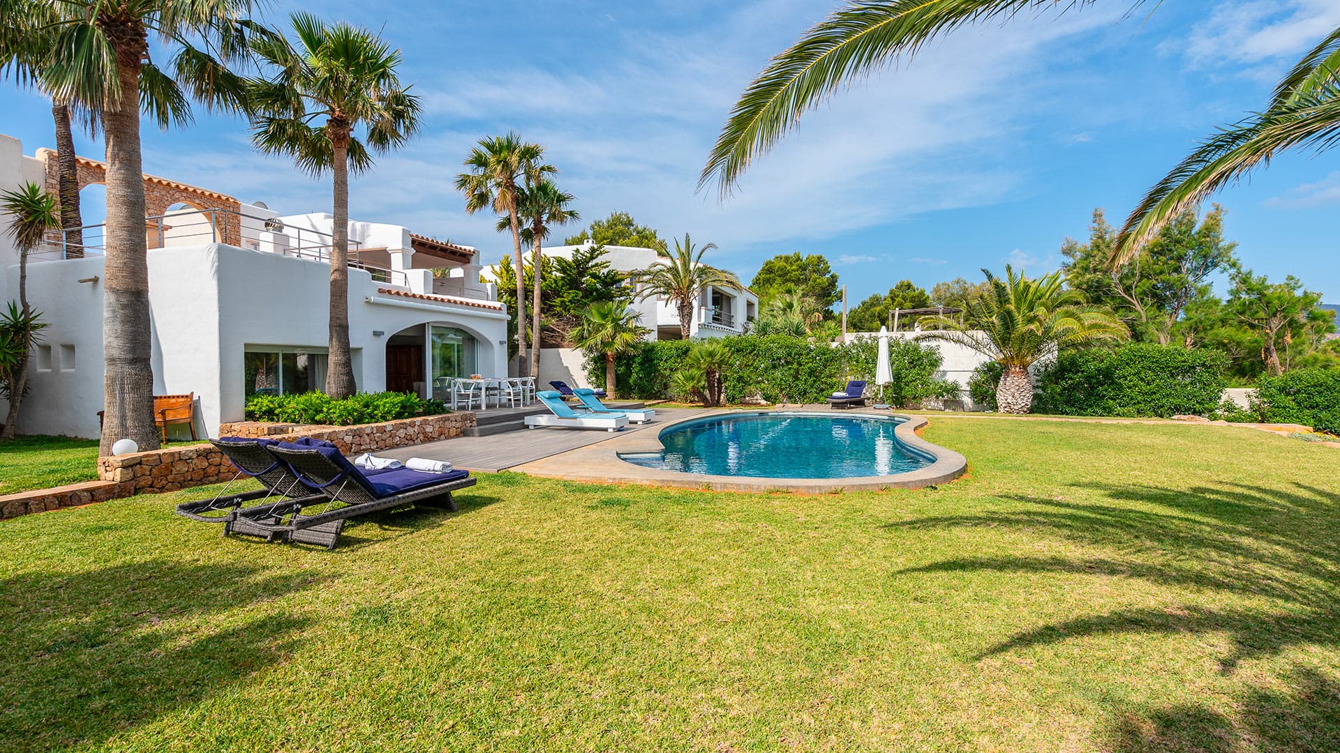 Mature palms around the swimming pool and lawn at Casa Porroig, Es Cubells, Ibiza
