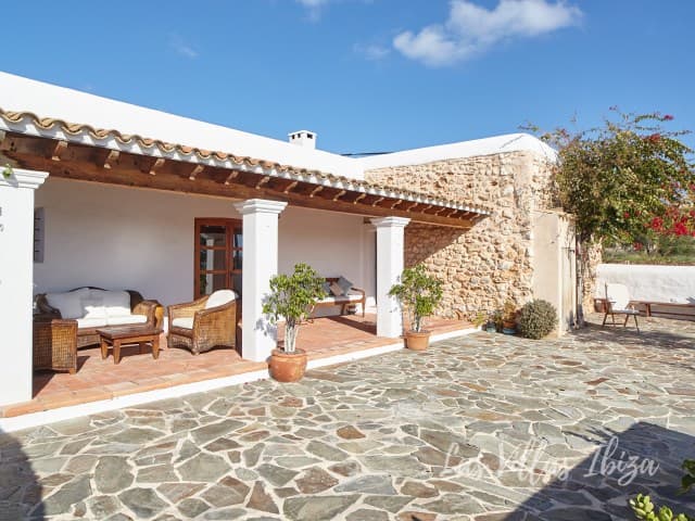 Stone paved terrace with seating beside the white facade at Villa Mariana, Sant Jordi de Ses Salines, Ibiza