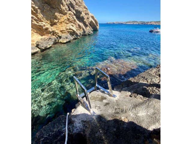Rocky cove with clear water and a bathing ladder below Can Rasa, Sant Josep, Ibiza