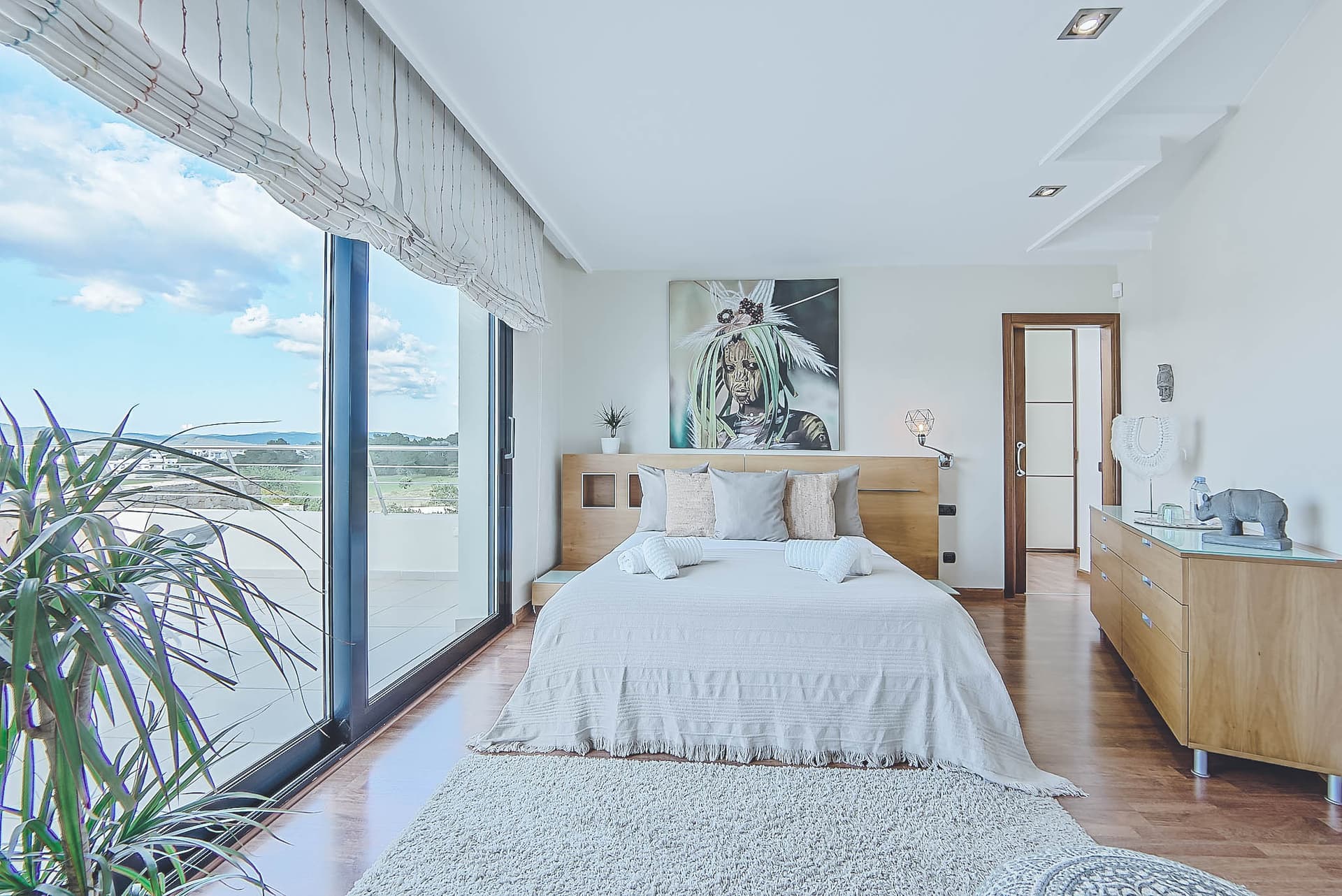 Bedroom with a full height glass wall opening to the terrace and countryside at Sa Salicornia, Sant Josep