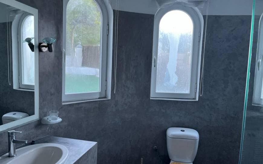 Bathroom in dark stone with arched windows at Can Kaila, Sant Josep, Ibiza