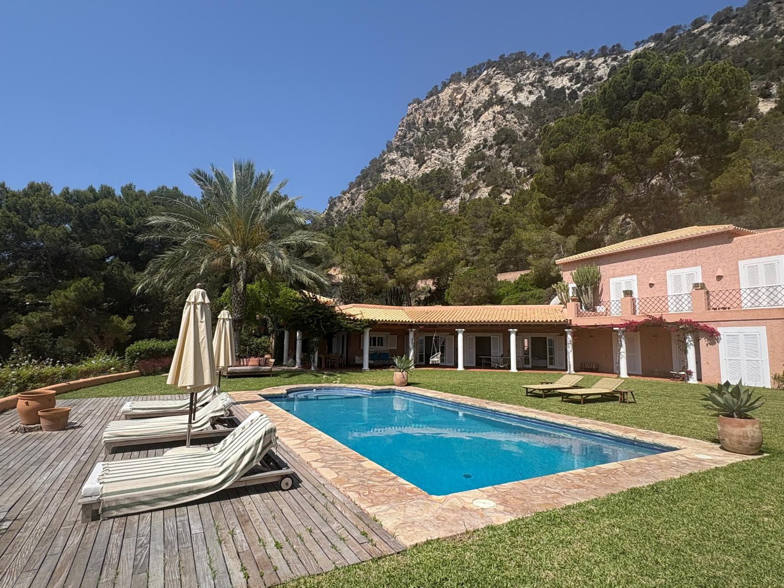 Long swimming pool with sun loungers below the mountain at Casa Hermosa, Es Cubells, Ibiza