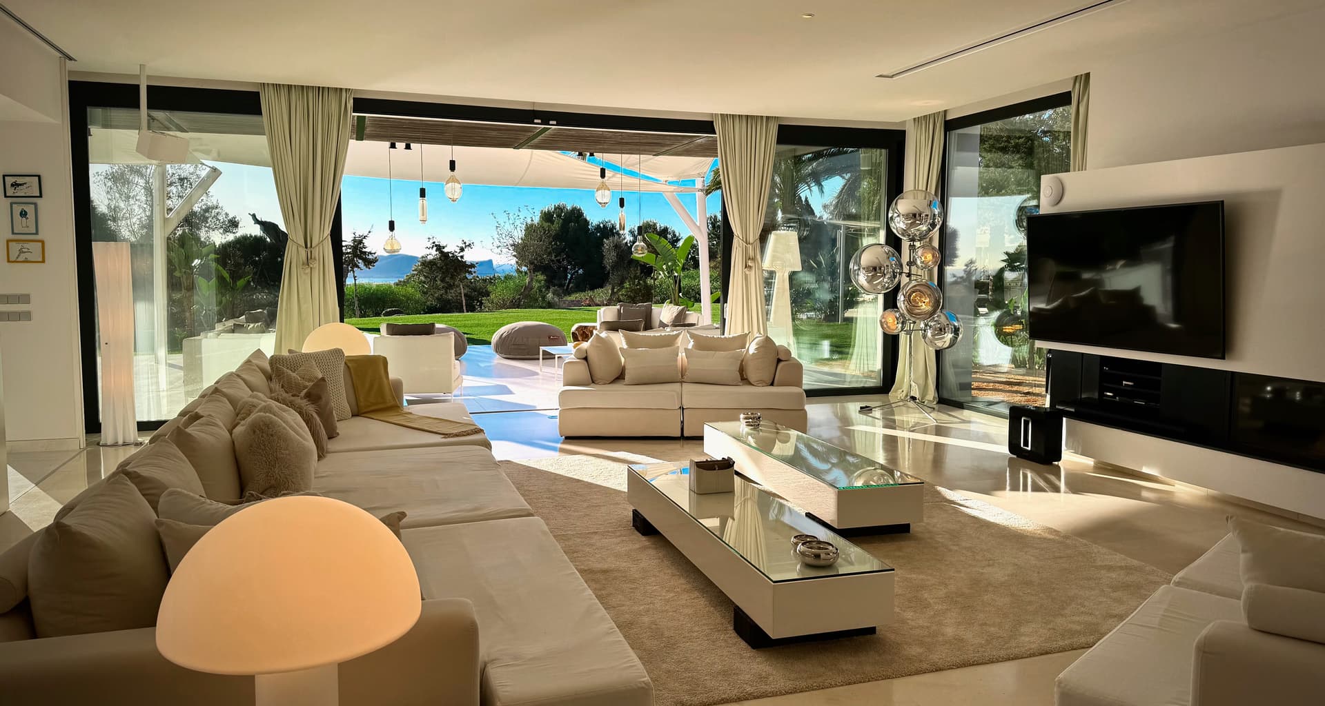 Living room with deep sofas and sliding glass onto the garden at Villa Ty, Ibiza