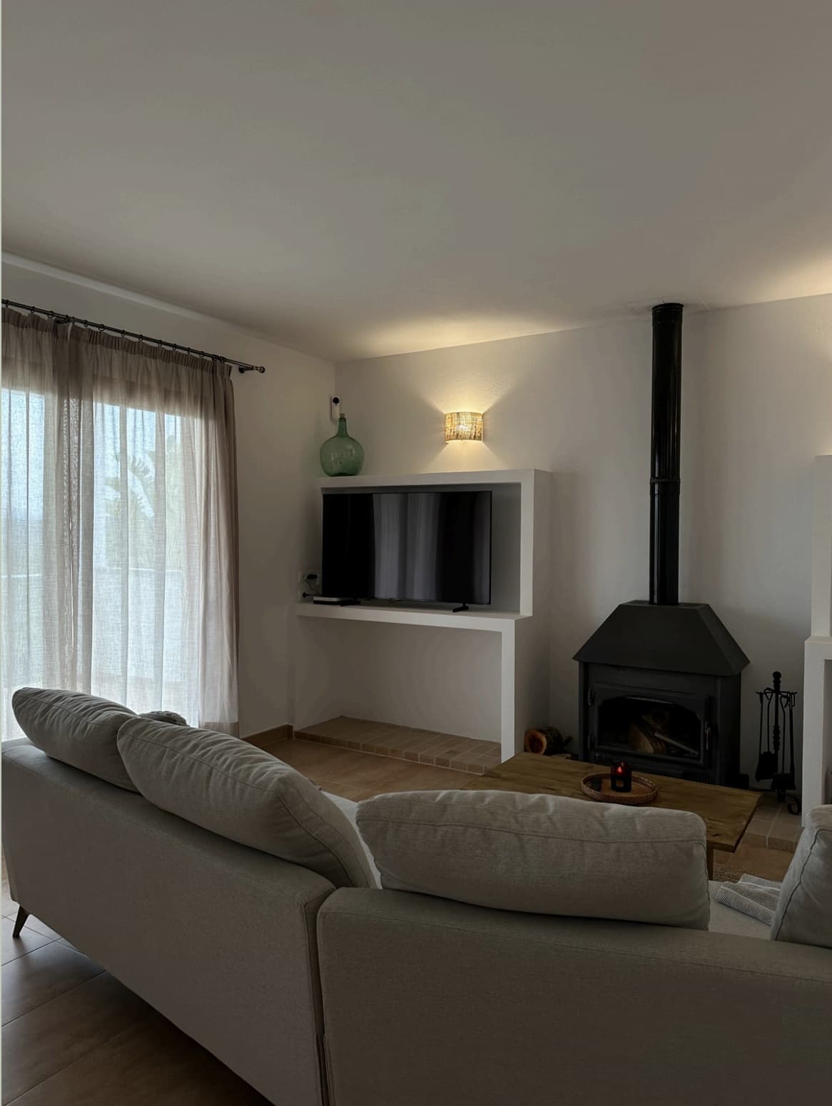 Living room with white sofas and a cast iron wood stove at Can Cata, Santa Gertrudis, Ibiza