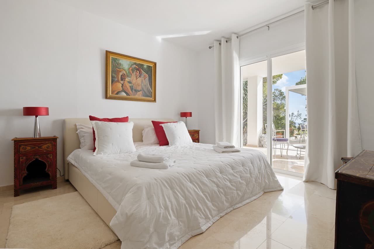 White bedroom with red accents and doors to the terrace at Villa Rome, Es Cubells, Ibiza