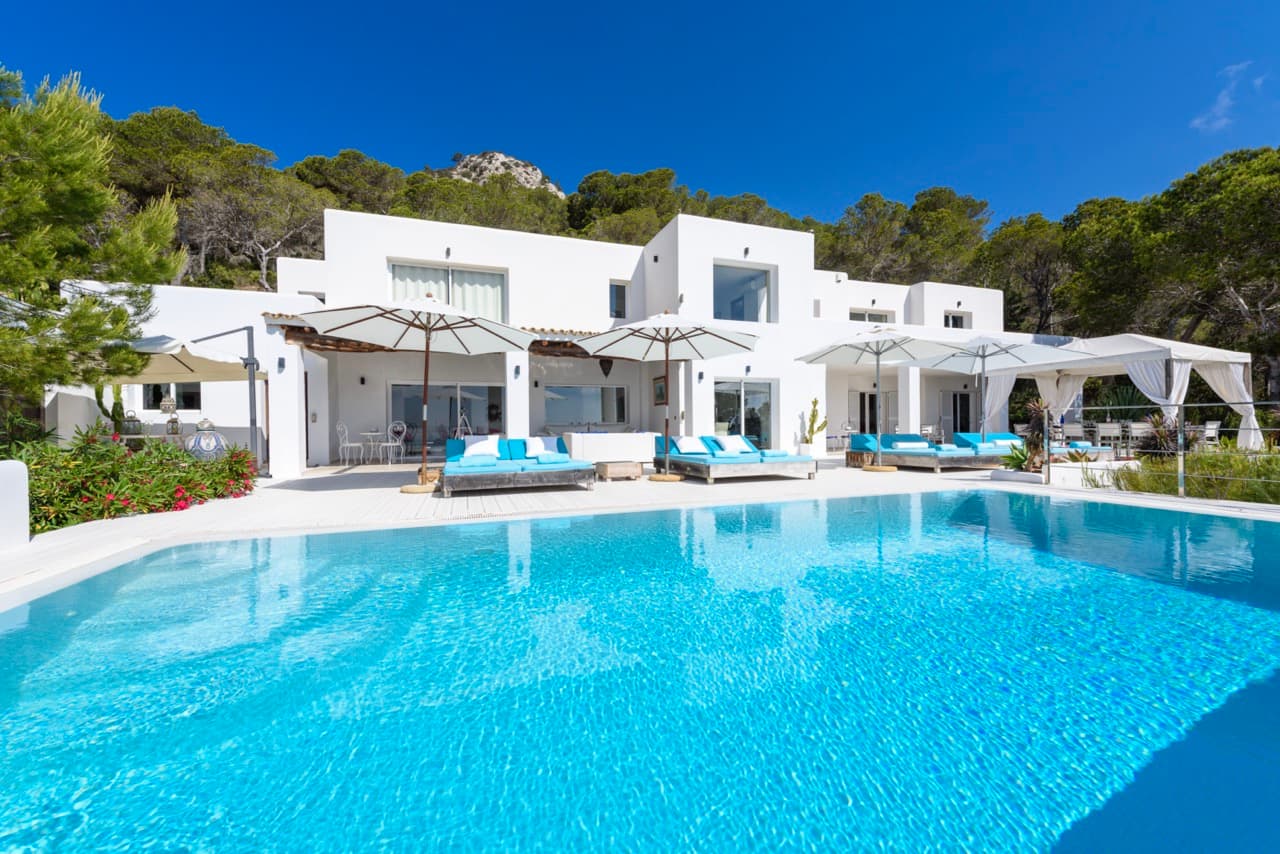 Large swimming pool with blue loungers below the whitewashed terraces at Villa Rome, Es Cubells, Ibiza
