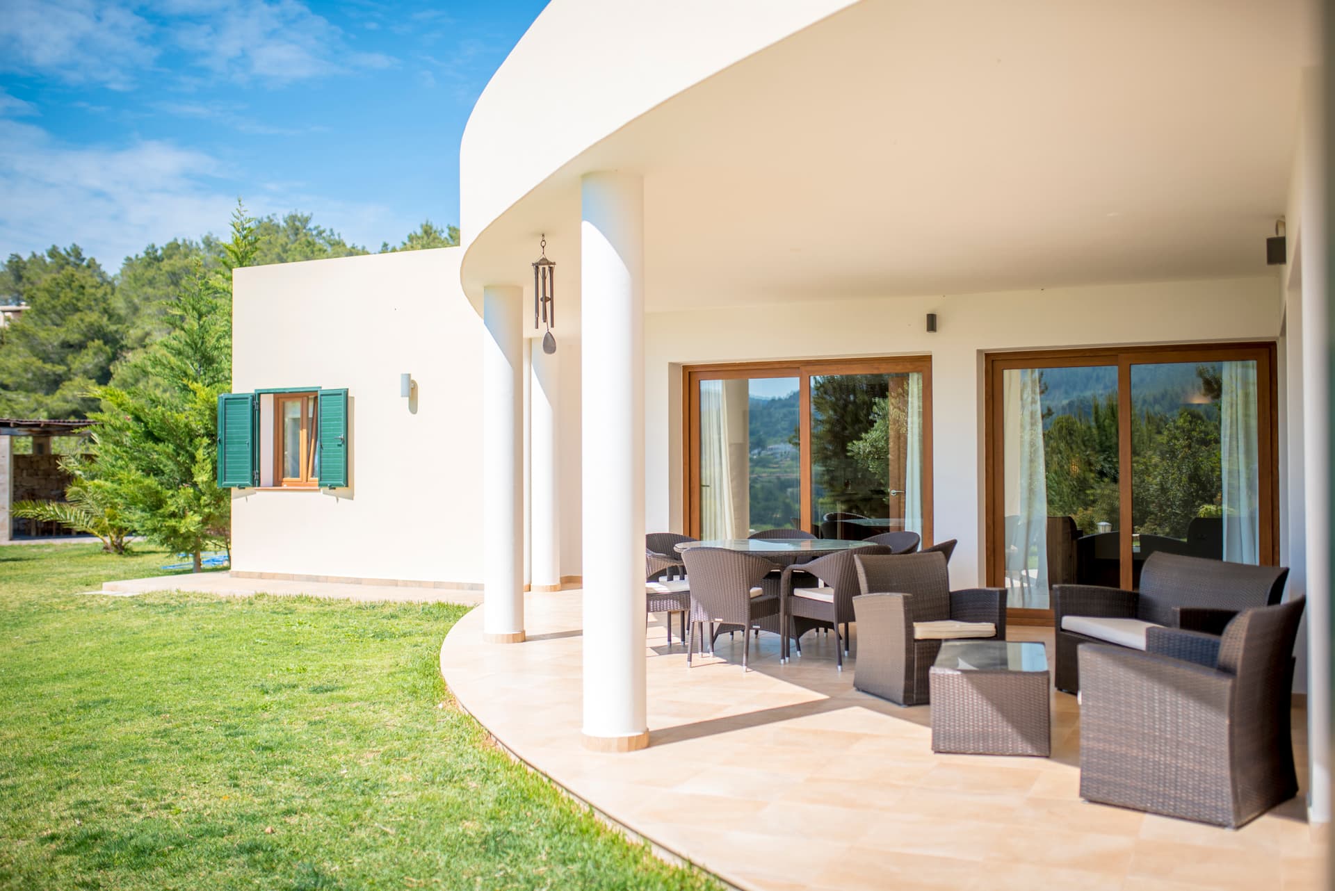 Curved whitewashed facade and lawn with terrace seating at Villa Sa Lluna, Sant Josep de Sa Talaia, Ibiza