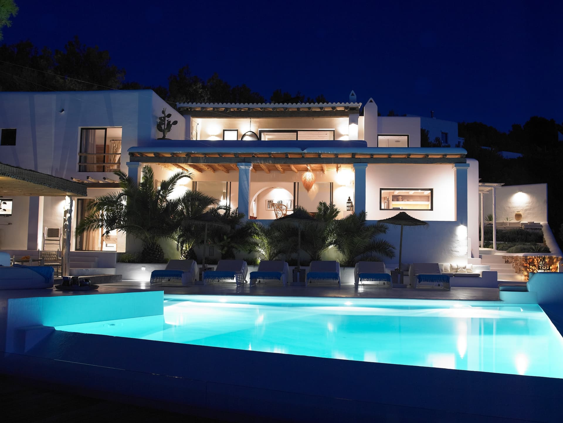 Swimming pool lit at dusk below the glazed living spaces at Can Heart, Cala Moli, Ibiza