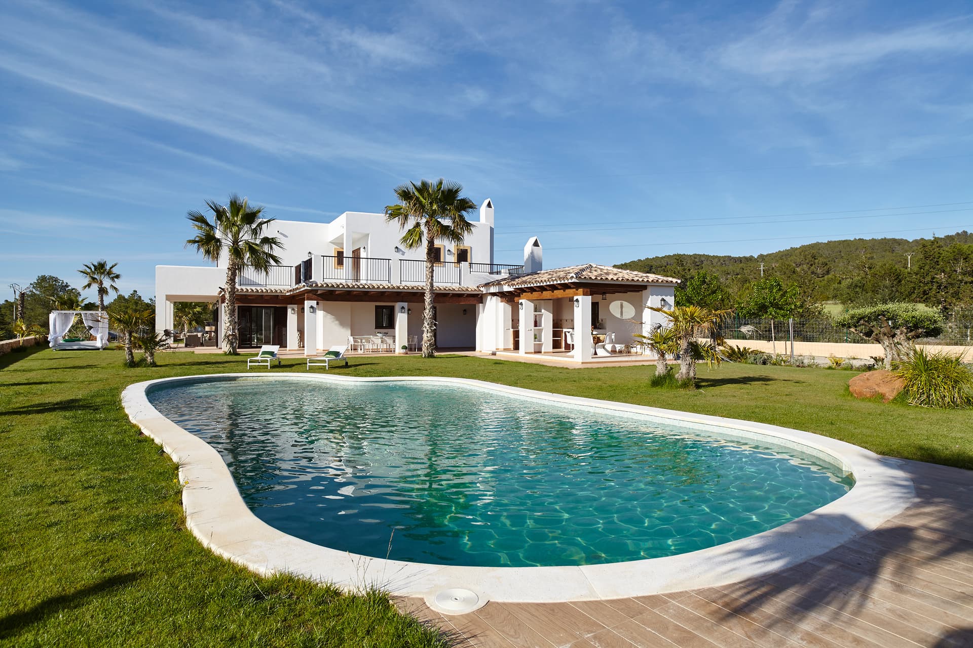 Curved swimming pool set in the lawn below the house at Can Hesper, Benimussa, Ibiza