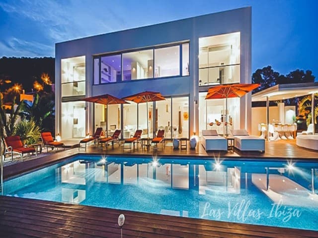 Contemporary villa lit at dusk with terrace seating beside the pool at Villa Serenity, Es Cubells, Ibiza