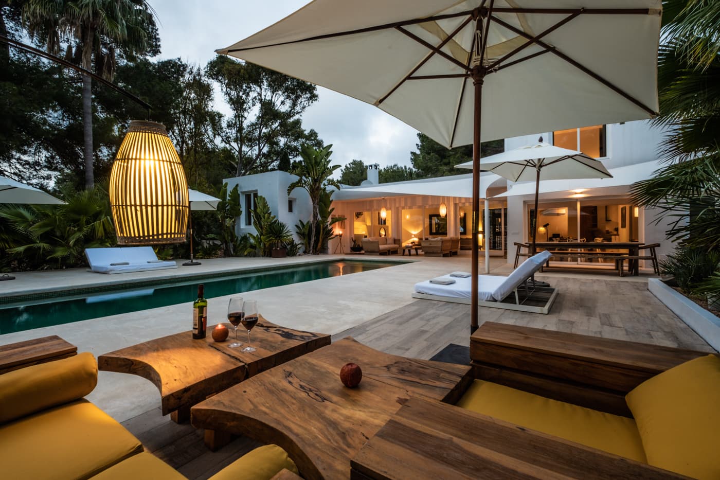 Terrace with a parasol and woven lamp beside the pool at dusk, Villa Zola, Roca Llisa, Ibiza