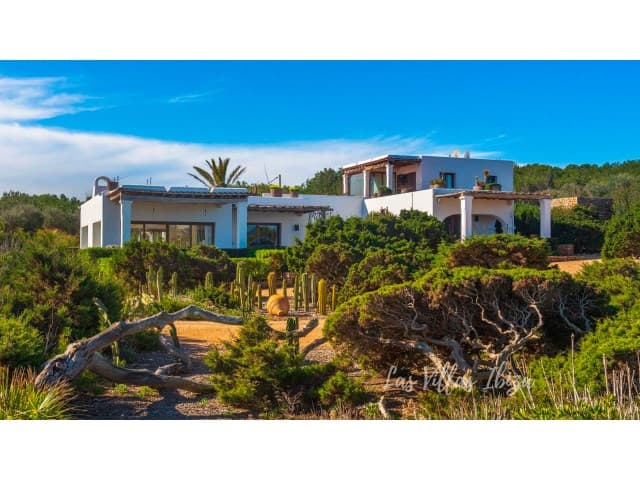 White villa set among coastal scrub above the shore at Villa Bellalux, Sant Carles, Ibiza