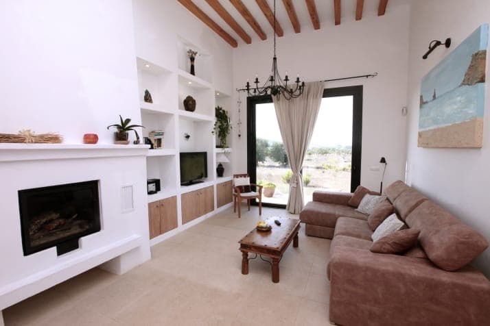 White living room with a corner fireplace and beamed ceiling at Villa Ruisenor, Sant Joan de Labritja, Ibiza