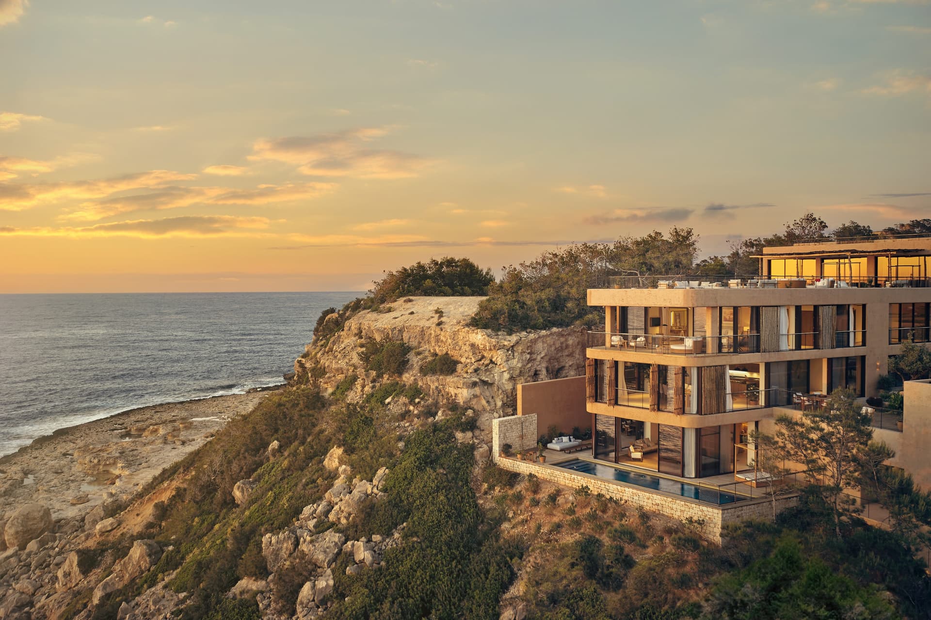 Mansion set on the cliff edge above the sea at sunset, Portinatx, Ibiza