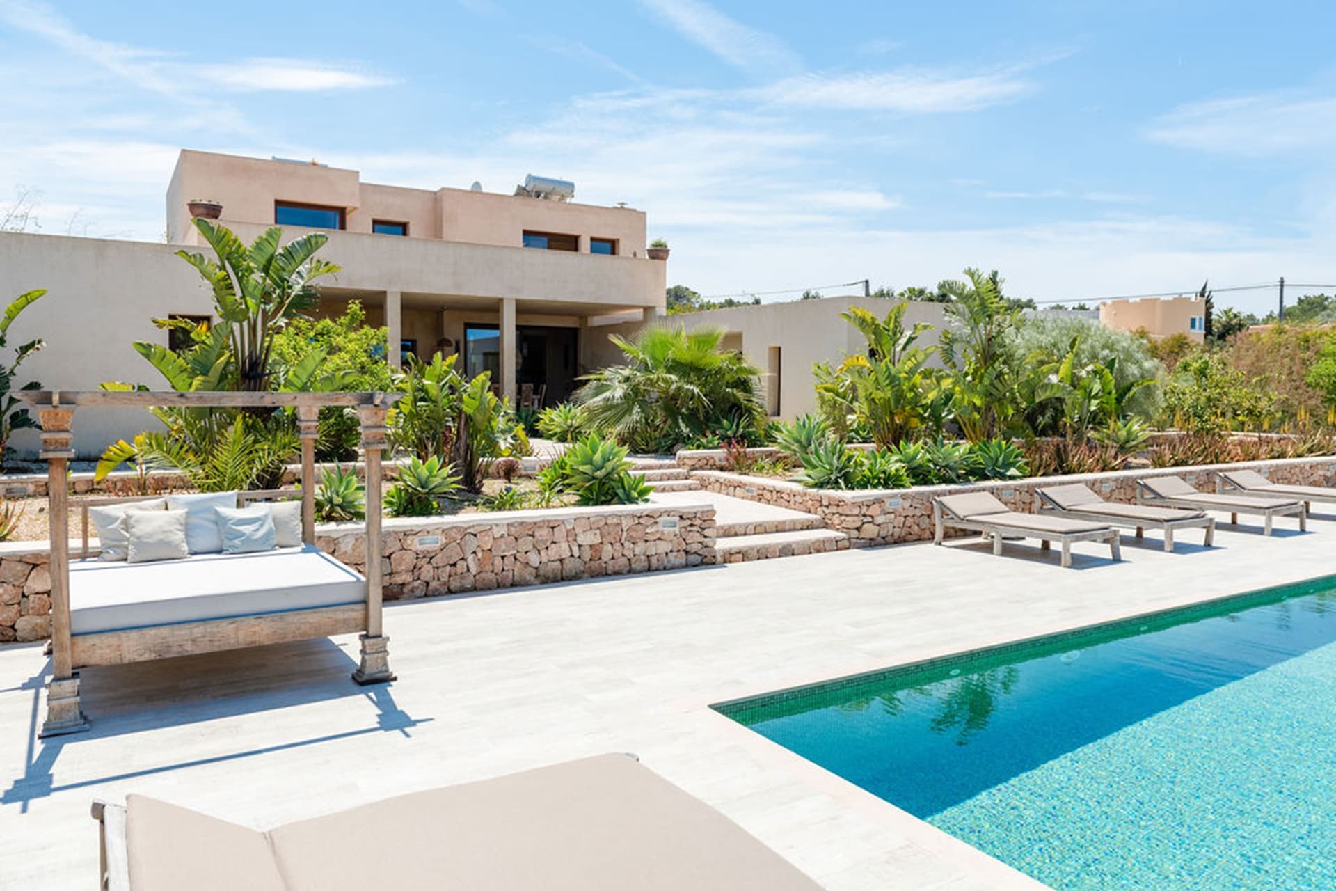 Swimming pool and daybeds below the sandstone facade at Villa Shan, Sant Agusti, Ibiza