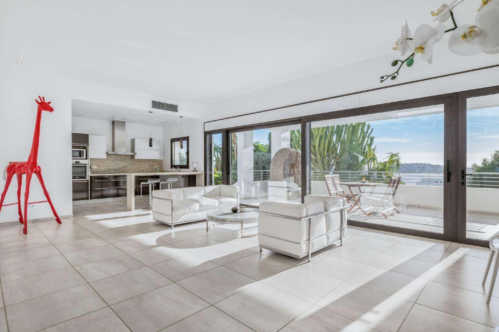 White living room with sliding glass opening towards the bay of Talamanca at Villa Misada, Ibiza
