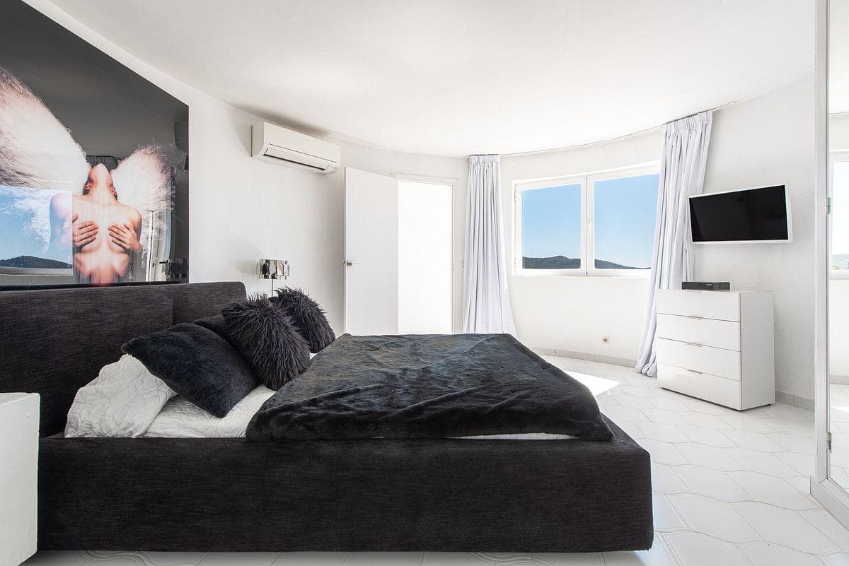 Bedroom with contemporary artwork and the sea beyond at Vista Choiba, Es Cubells, Ibiza