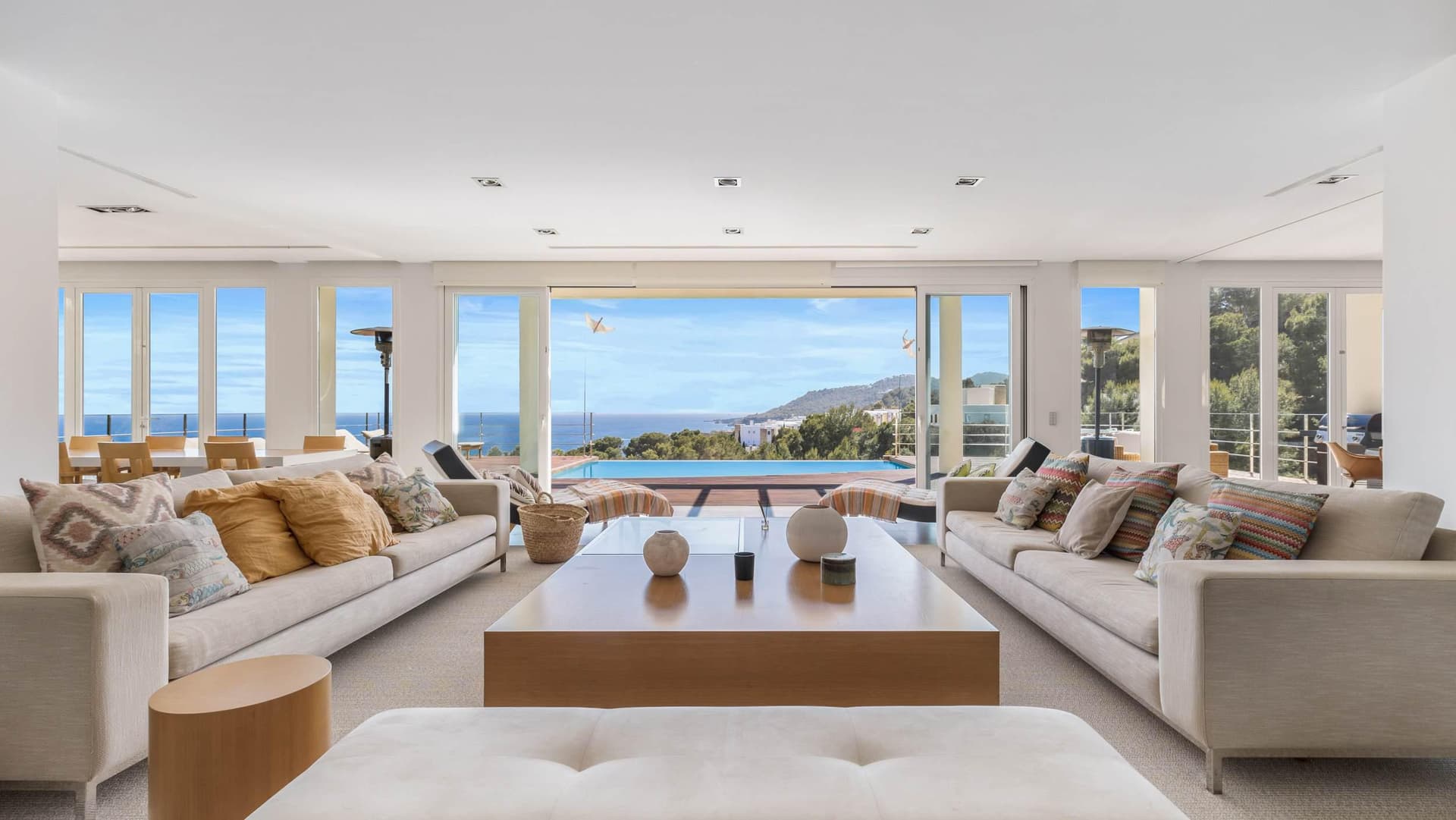 Living room with white sofas and a timber table looking out to sea at Villa Blue Rock, Roca Llisa, Ibiza