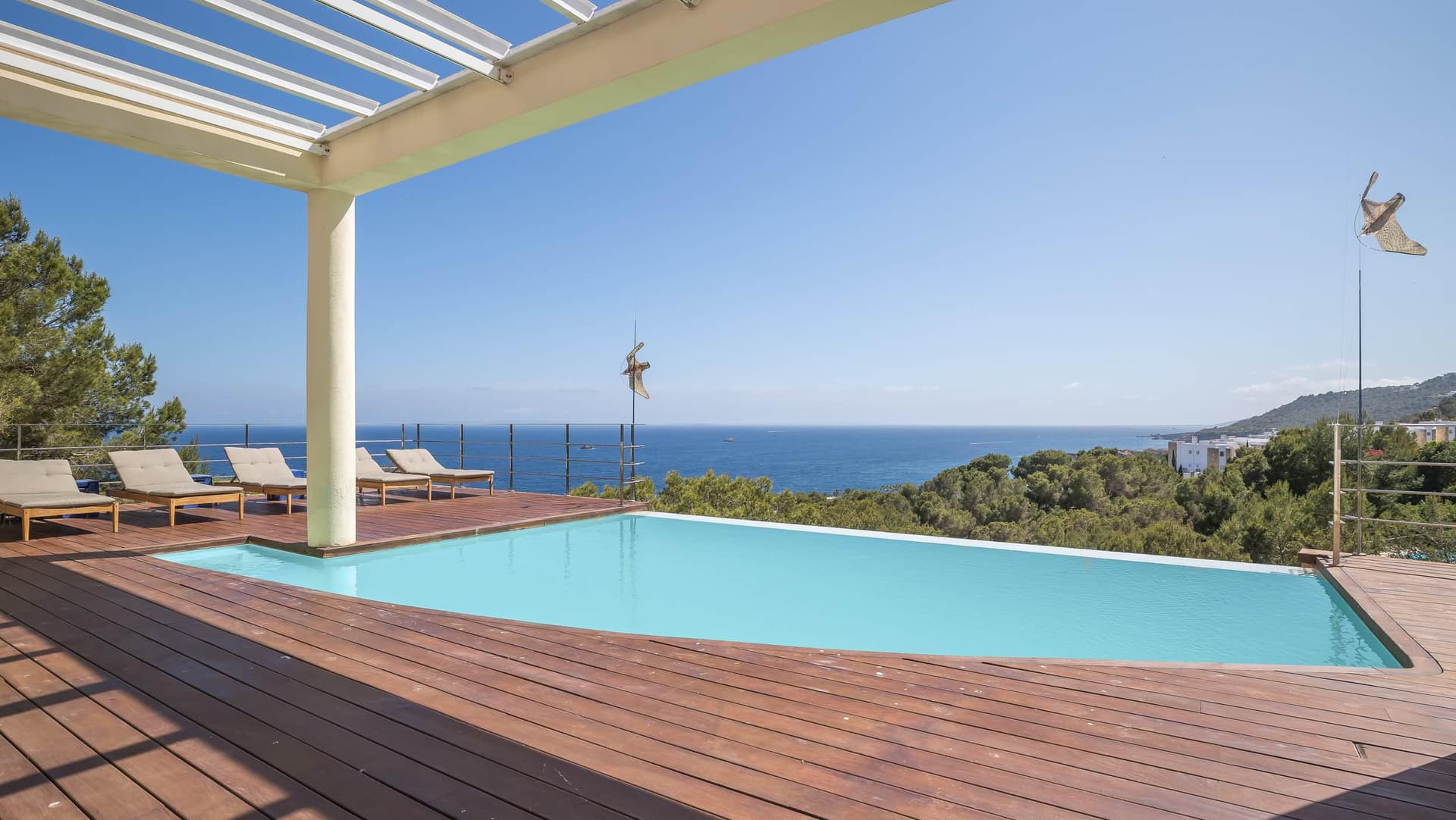 Timber pool deck beneath a pergola with the sea beyond at Villa Blue Rock, Roca Llisa, Ibiza