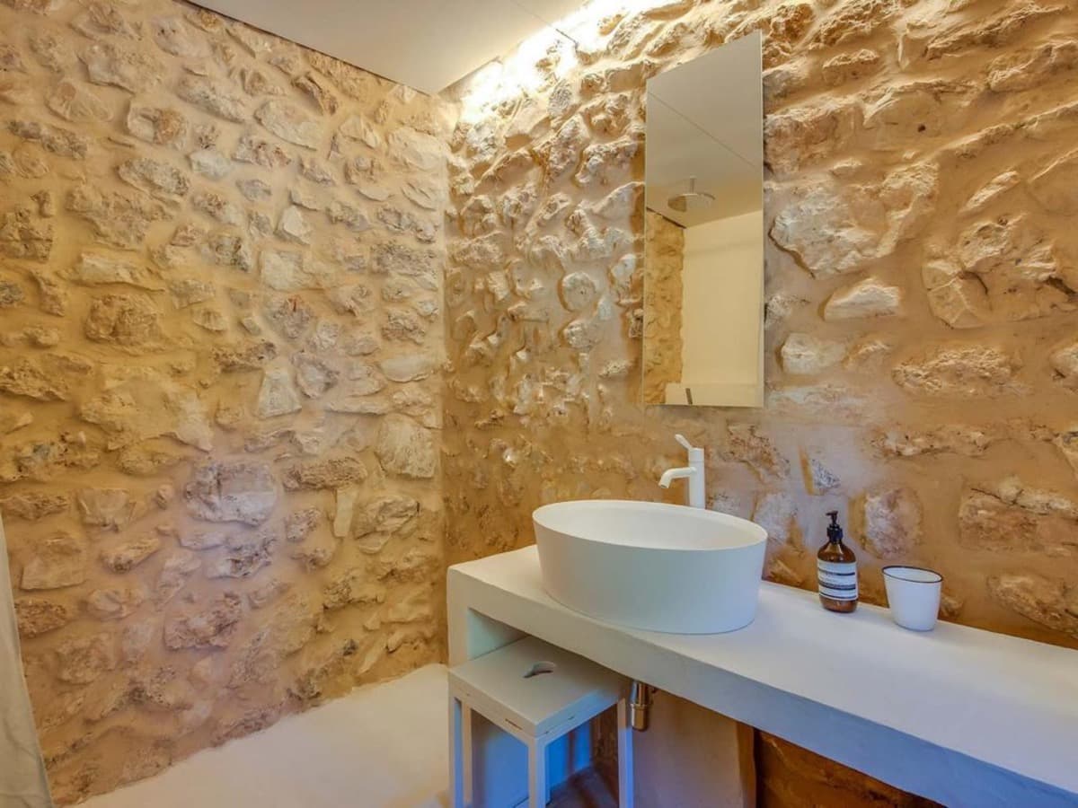 Bathroom with a stone wall and stone basin at Can Lucy Jondal, Cala Jondal, Ibiza