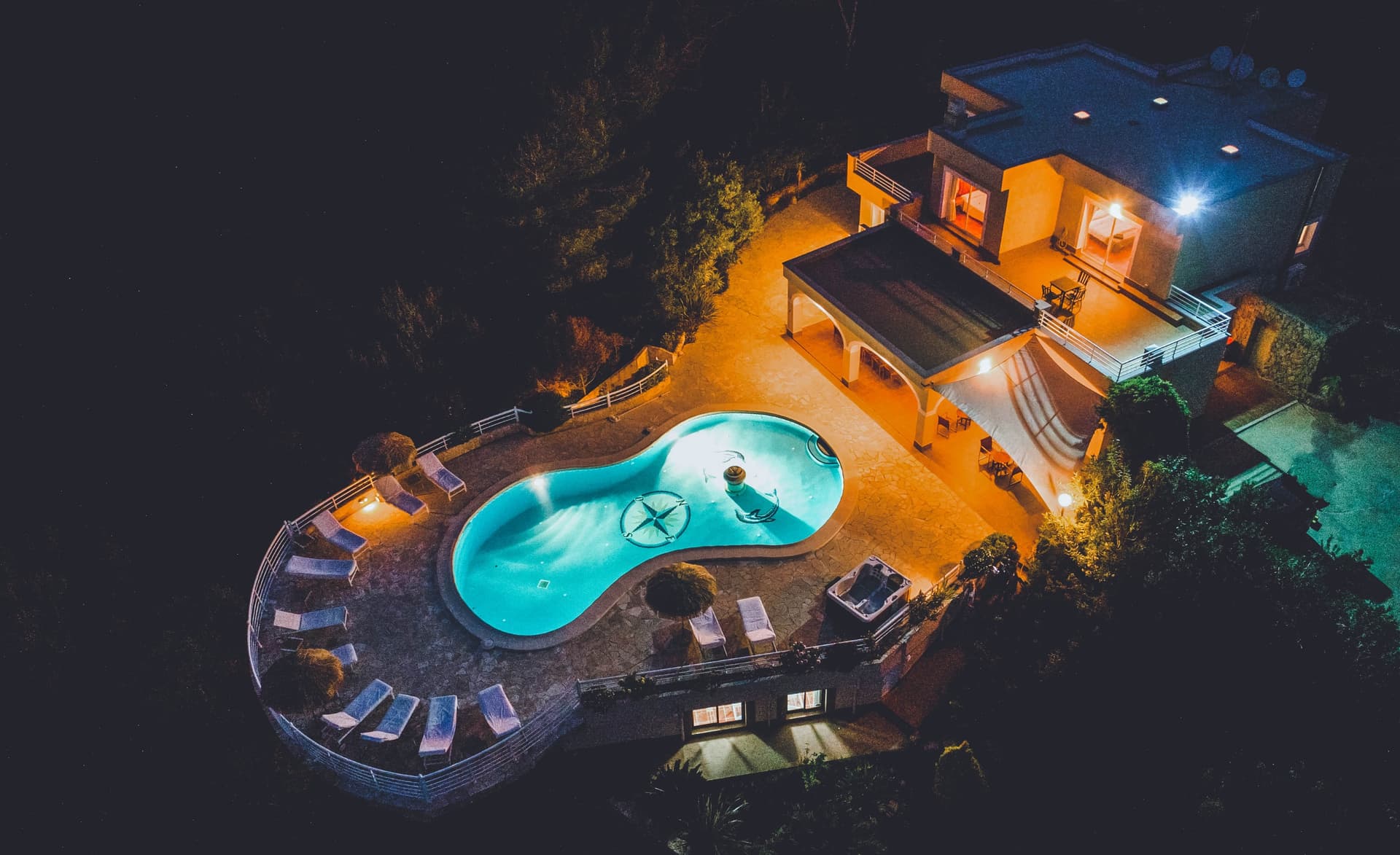 Aerial view of Villa KM4 lit at night with its pool and terraces, Sant Josep, Ibiza