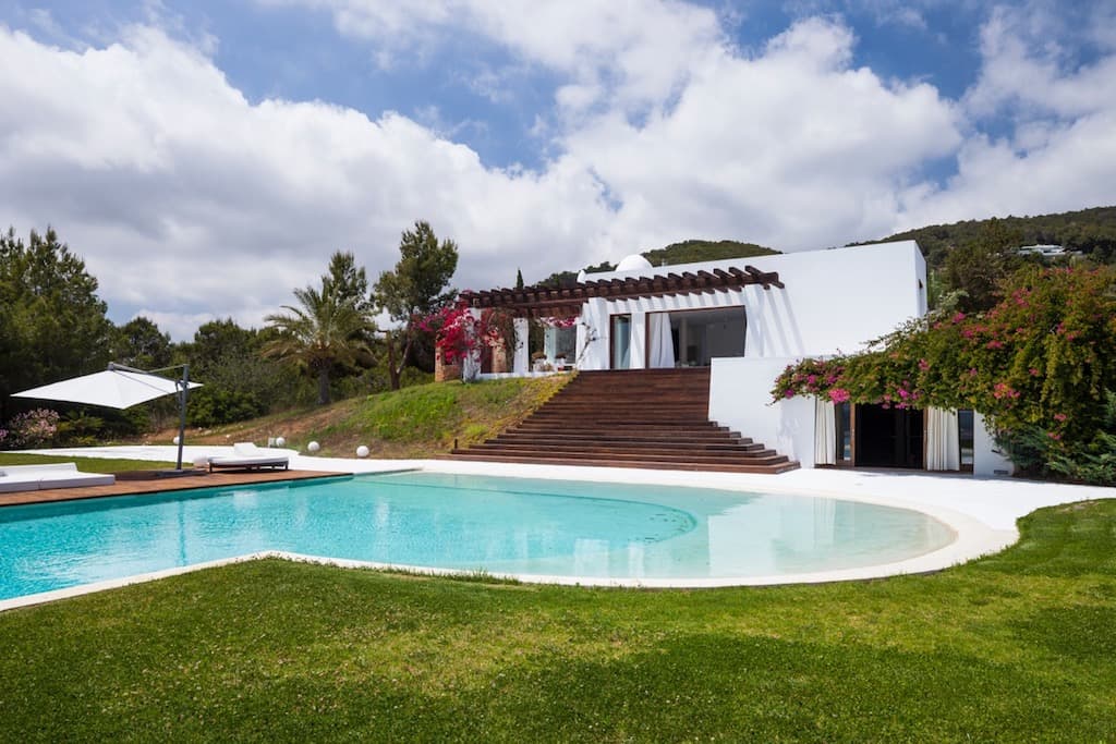 Curved swimming pool set into the lawn below the house at Villa Margo, Sant Josep, Ibiza