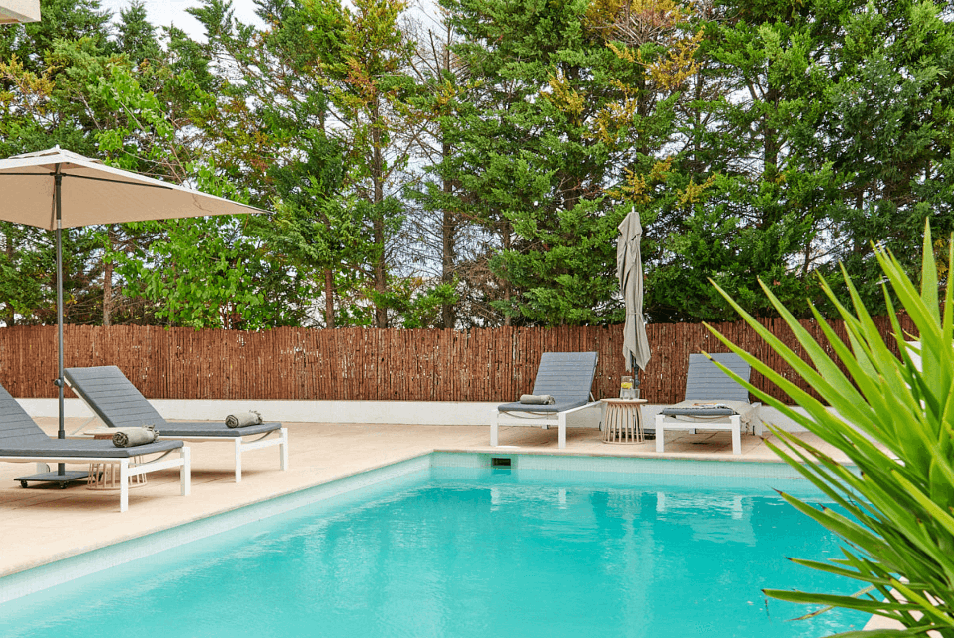 Sheltered swimming pool with a parasol behind a clipped hedge, a quiet house in Jesus, Ibiza