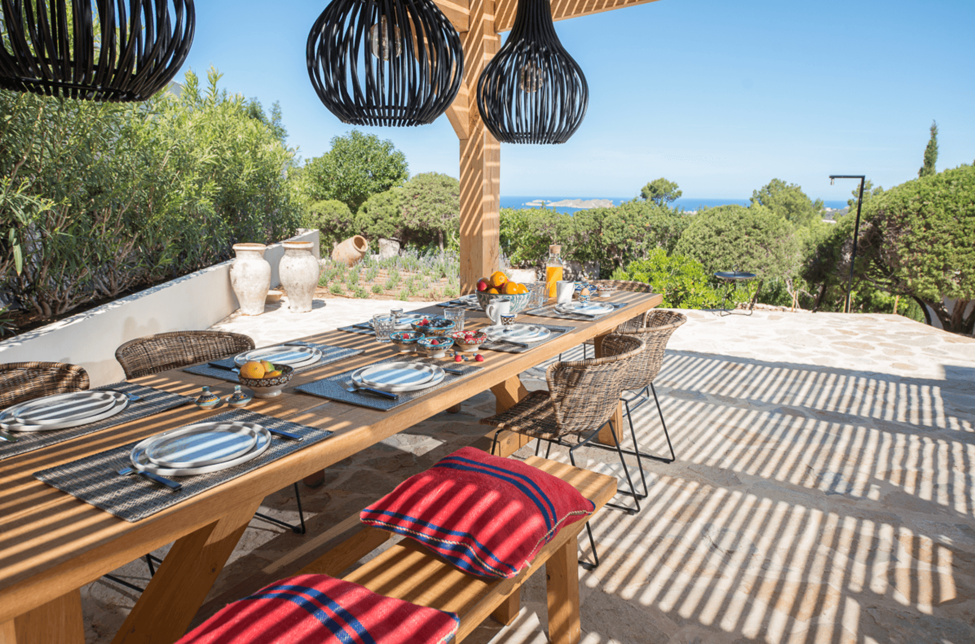 Outdoor dining on a timber deck beneath woven pendant lights, Sant Josep, Ibiza