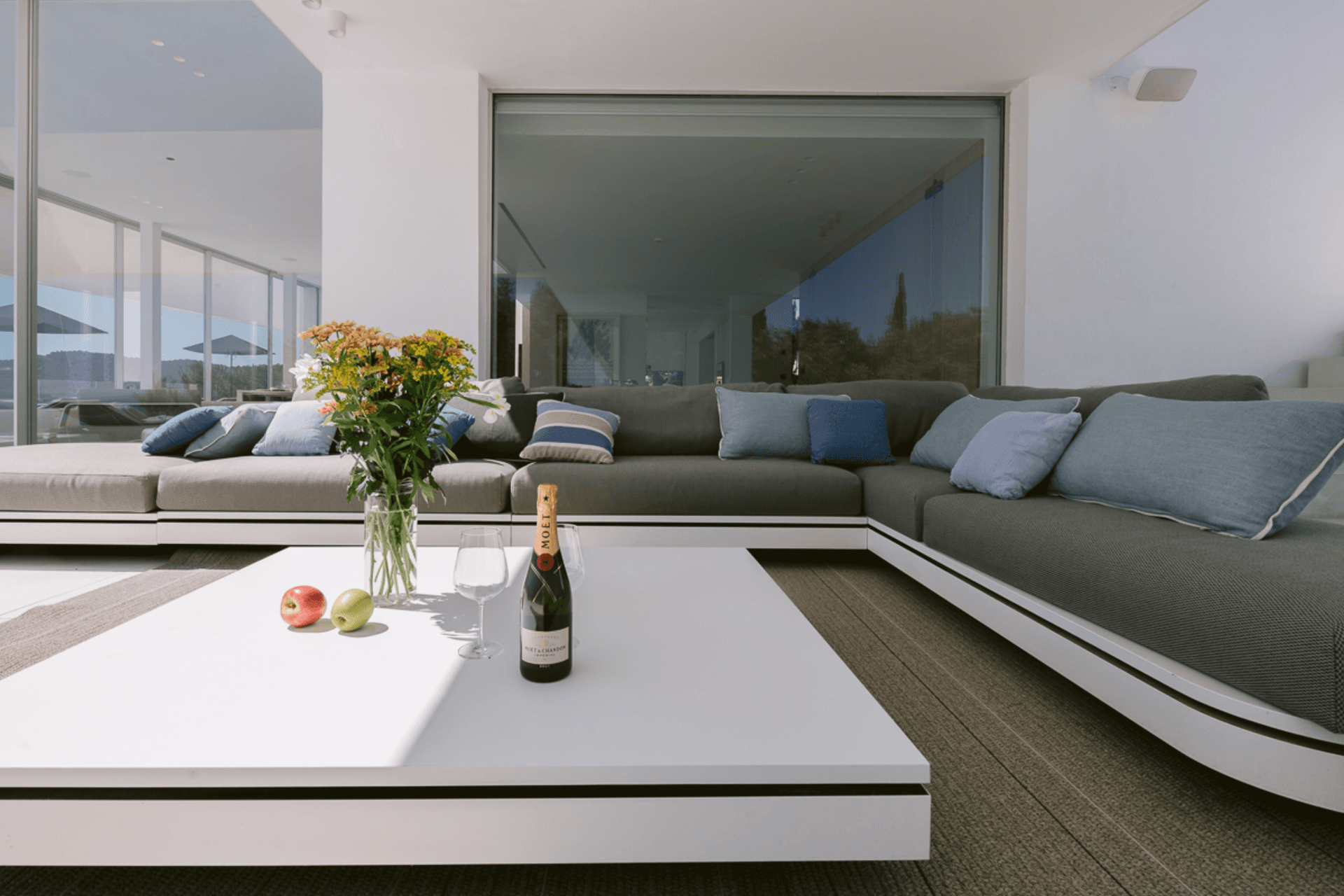 Living room with soft grey seating opening to the terrace in a newly built villa, Ibiza