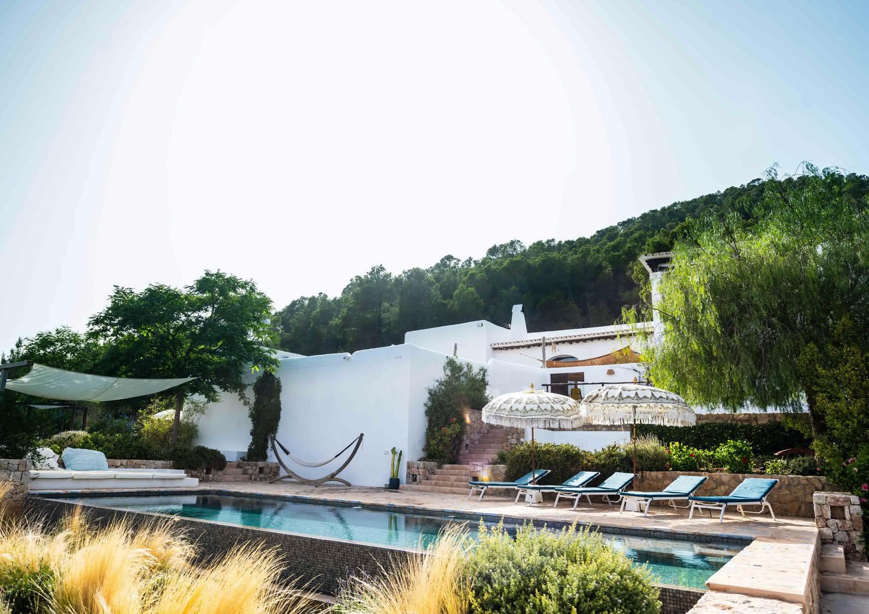 Swimming pool with sun loungers below the wooded hills at Can Luke, Ibiza