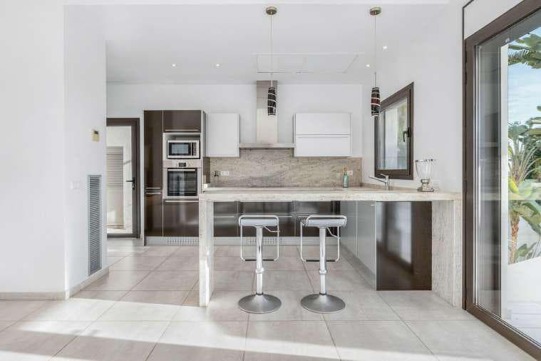 White kitchen with a breakfast island and bar stools at Villa Misada, Talamanca, Ibiza